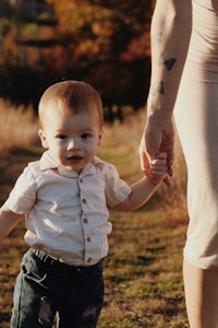 a woman holding a child's hand in a field