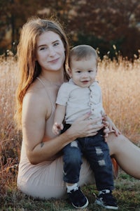 a woman holding a baby in a field