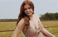 a woman sitting on a bench in a field