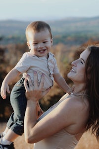 a woman holding a baby in her arms in a field