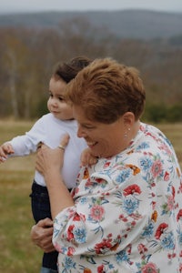 an older woman holding a small child in a field