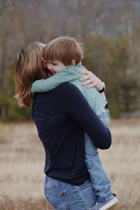 a woman is hugging her son in a field