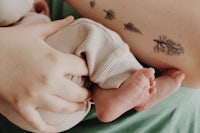 a woman holding a baby with a tattoo on her arm