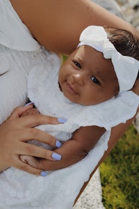 a woman holding a baby in a white dress