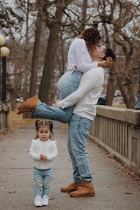 a family is holding a little girl in their arms while walking on a bridge