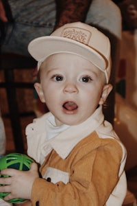 a baby wearing a hat and holding a ball