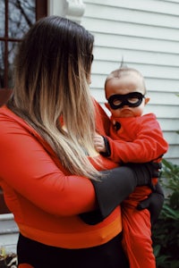 a woman holding a baby in an incredibles costume