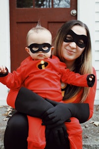 a woman dressed as the incredibles holding a baby