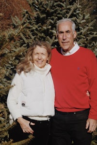 a man and woman standing in front of a christmas tree