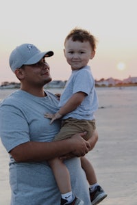 a man holding his son on the beach at sunset