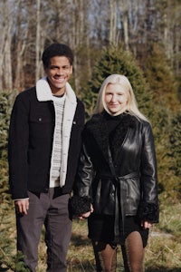 a man and woman standing in front of a christmas tree farm