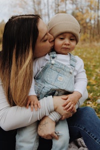 a woman kisses her son in the park