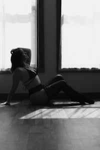 a woman in lingerie laying on the floor in front of a window