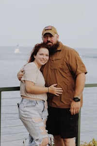 a man and woman posing in front of the ocean