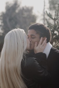 a couple kissing in front of a tree