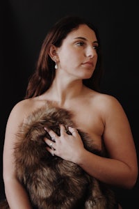 a woman in a bikini posing with a fur coat