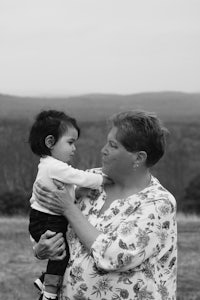 black and white photo of a woman holding a child in a field