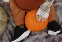 a child playing with a pumpkin on a blanket