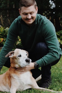 a man petting a dog in the grass