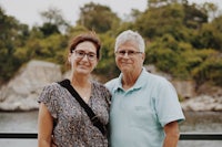 an older couple posing for a photo near a body of water