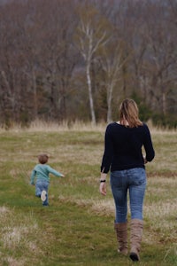 a woman and a child walking through a field