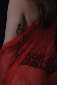 a woman in a red lace dress with a tattoo on her back