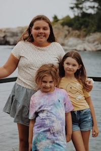 three girls posing for a photo by the water