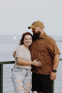 a man and woman posing for a photo by the water