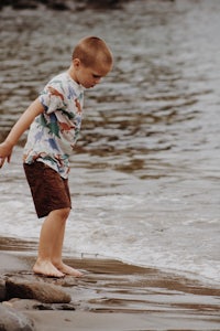 a young boy standing on a beach with a frisbee