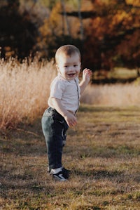 a baby standing in a field with tall grasses