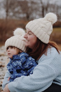 a woman and a child sitting on rocks with hats on