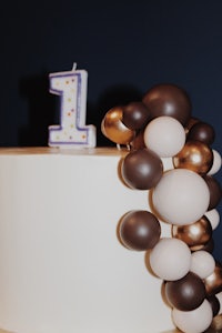 a cake decorated with balloons and a candle