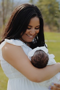 a woman holding a baby in a field