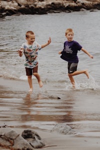 two boys running in the water near a body of water