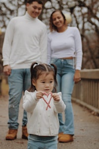 a family with a little girl holding a heart shaped piece of paper