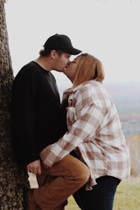 a couple kissing in front of a tree