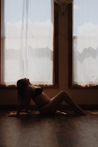 a woman laying on the floor in front of a window