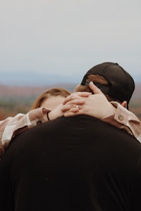 a man and woman hugging in front of a mountain