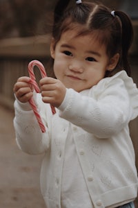 a little girl holding a candy cane