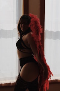 a woman in black and red lingerie posing in front of a window