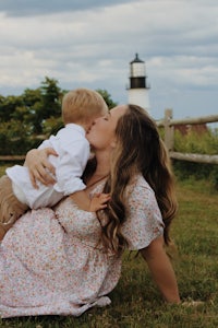 a woman kissing her son in front of a lighthouse