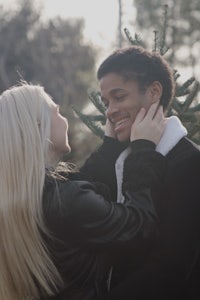 a man and woman hugging in front of a christmas tree