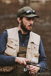 a man wearing a hat and vest is holding a fishing rod