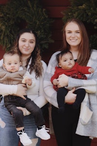 three women holding their children in front of a christmas wreath