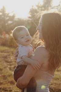 a woman holding a baby in a field