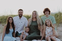 a family sits on a blanket on the beach