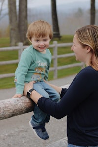 a woman holding a child on a wooden fence