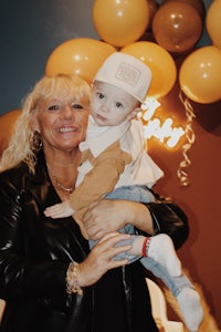 a woman holding a child in front of balloons