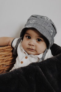 a baby wearing a hat in a basket