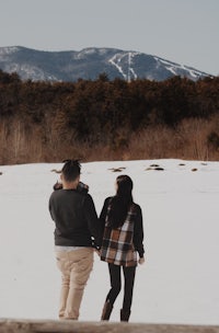 a couple walking in the snow with mountains in the background